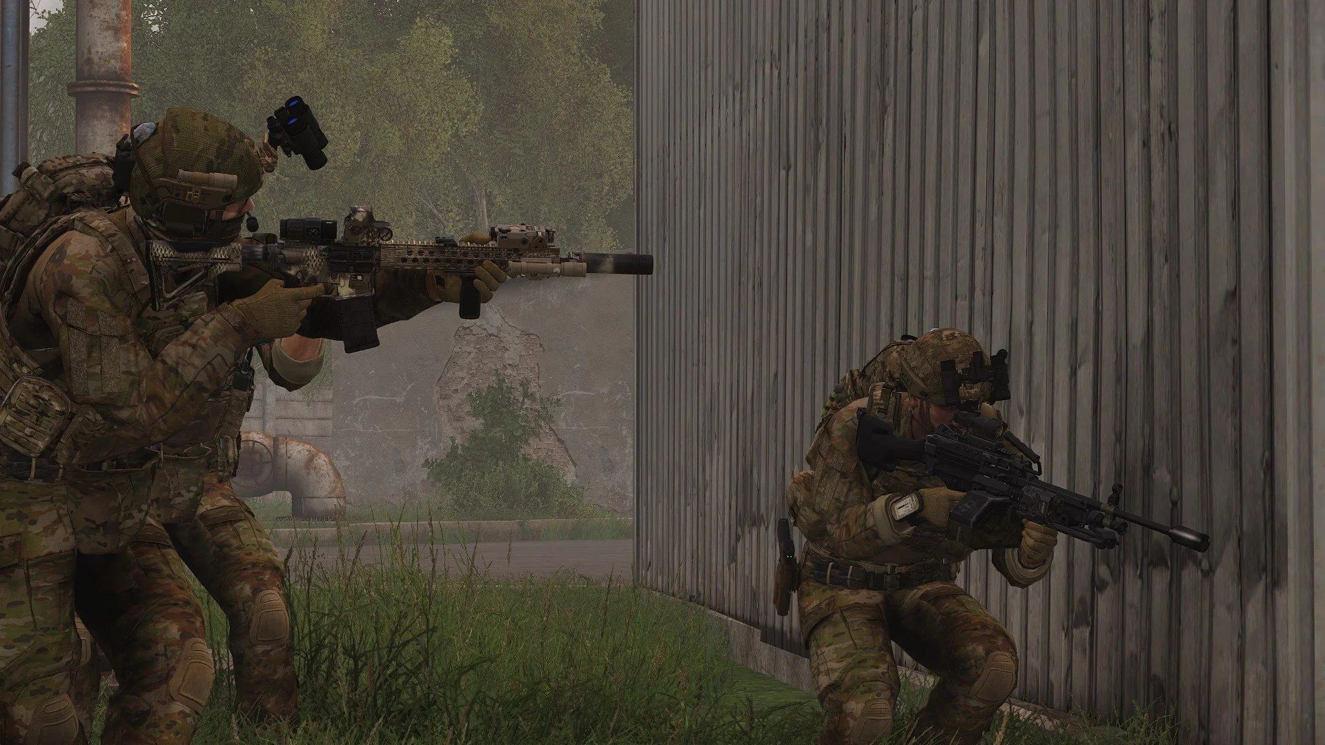 Two soldiers in camouflage gear aiming rifles behind a wooden wall, with one soldier crouching and the other standing, in an outdoor setting.