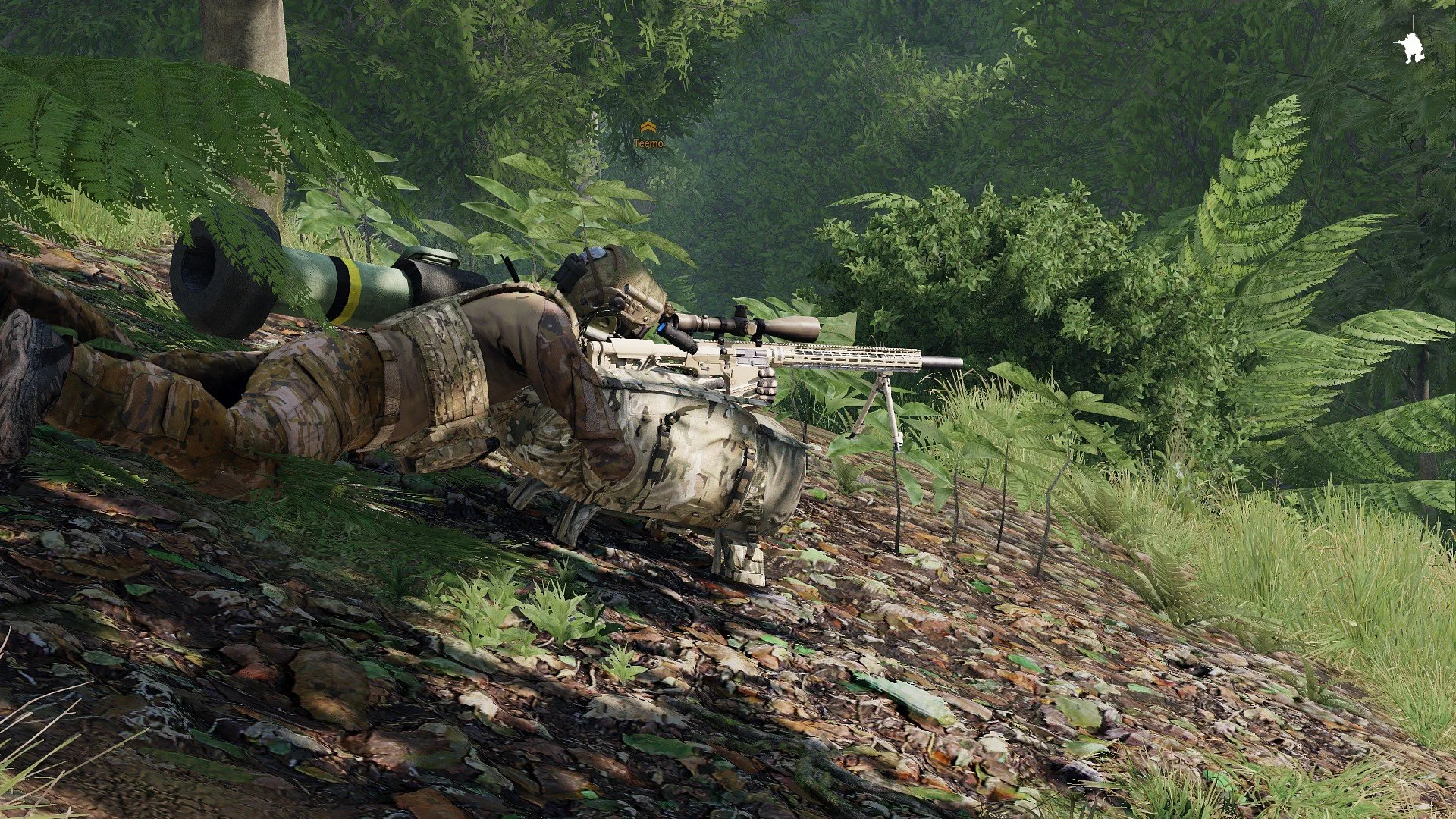 A soldier in camouflage gear lying prone on a forested hillside, aiming a sniper rifle through a scope, surrounded by lush green foliage and trees.