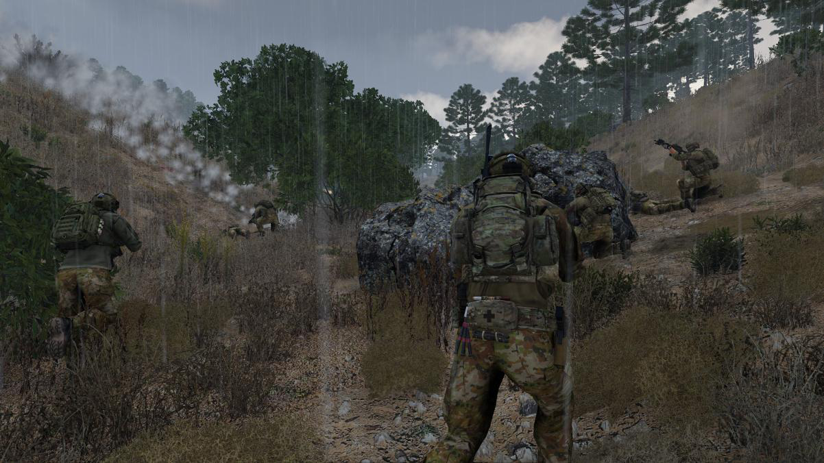 Soldiers in camouflage gear during a combat simulation or military operation in a forested area with rain and cloudy sky.
